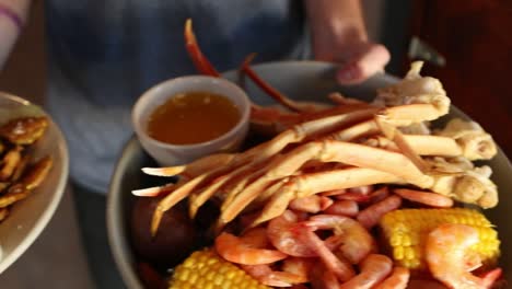 Two-plates,-one-with-a-variety-of-seafood-and-the-other-with-fried-pickles-and-ranch