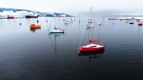 Eine-Ruhige-Flugreise:-Bunte-Boote-Treiben-Auf-Einem-See,-Der-Von-Schneebedeckten-Bergen-Gesäumt-Ist