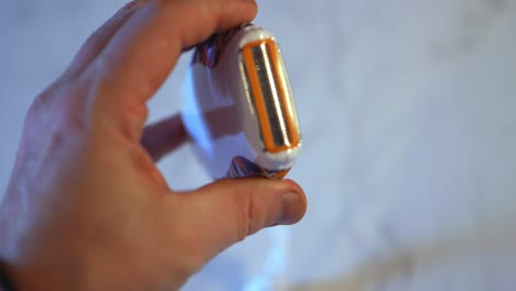 pequeña maquinilla de afeitar eléctrica de mano que obtiene la tapa superior de plástico volteada y vuelta a la cámara por mano blanca caucásica