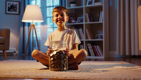 young boy saving coins in a glass jar at home