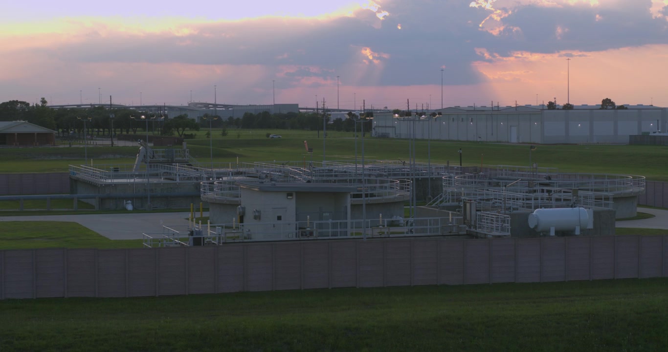 This birds eye drone view captures a wastewater treatment plant from directly overhead, showing the geometric layout of clarifiers, aeration basins, settling tanks, and other industrial infrastructure