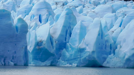 blue glacier melting into grey lake, slow motion