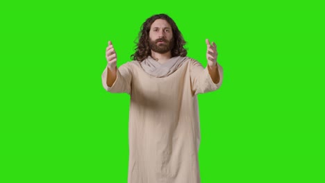 Studio-Shot-Of-Man-Wearing-Robes-With-Long-Hair-And-Beard-Representing-Figure-Of-Jesus-Christ-Praying-Or-Preaching-On-Green-Screen