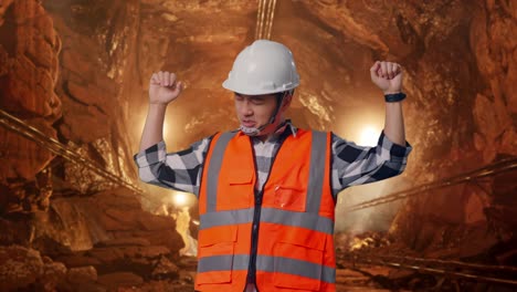 asian male engineer with safety helmet screaming goal and dancing celebrating in underground mine tunnel