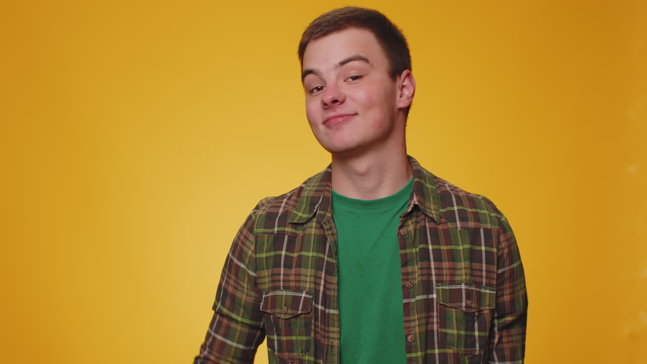 십대 젊은 남자가 카메라에 친절하게 미소 짓고 손을 흔들며 인사하거나 작별 인사를 합니다.