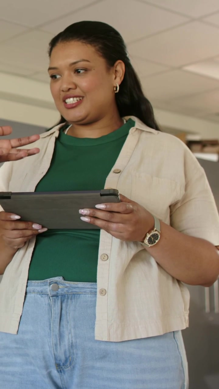 Vertical video: Holding tablet, woman checking info after coworker gesture in office watch showing