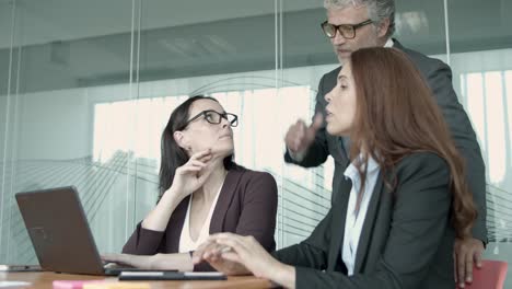 senior manager in glasses talking with young female employees