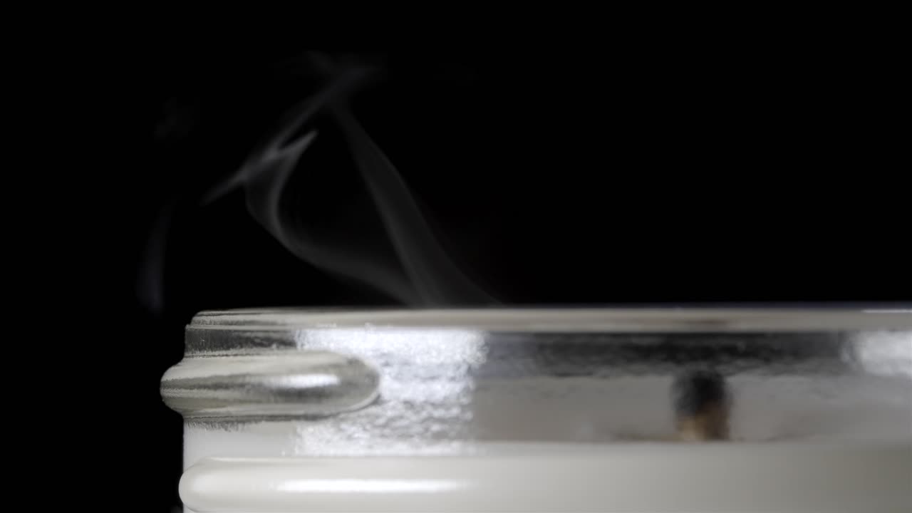 Watch the beautiful moment of a candle flame slowly extinguishing in the dark.