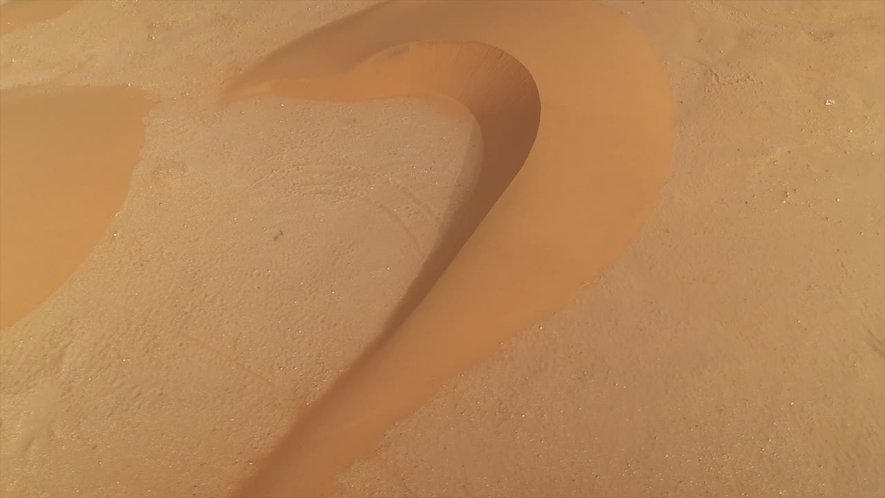 Aerial footage of wind-sculpted sand dune patterns and textures in El Agunia, Morocco, Africa, Nature background. Drone top-down view