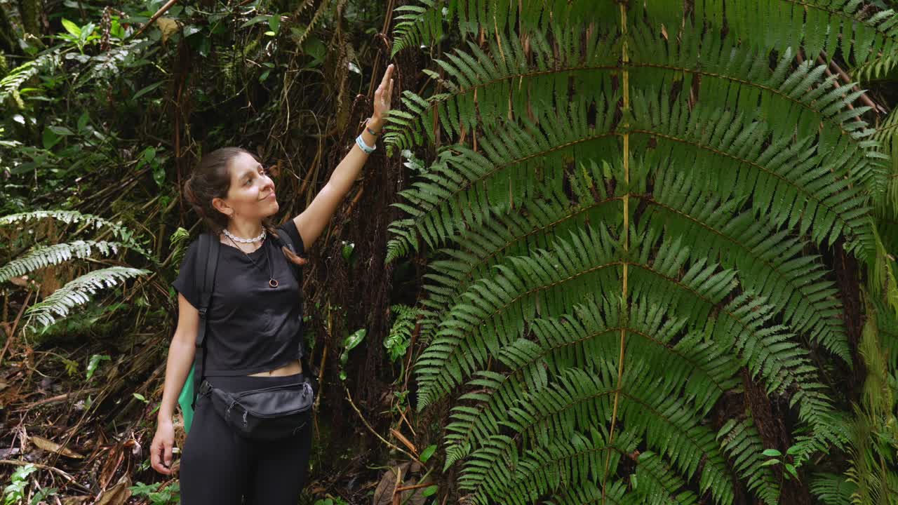 Woman next to giant fern Andean forest environment Colombia jungle
