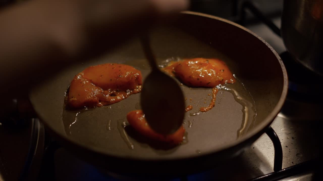 Laying marinated chicken in honey and spices on a hot pan