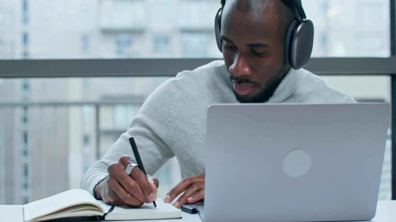 hombre trabajando en la computadora portátil y tomando notas
