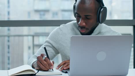man working on laptop and taking notes