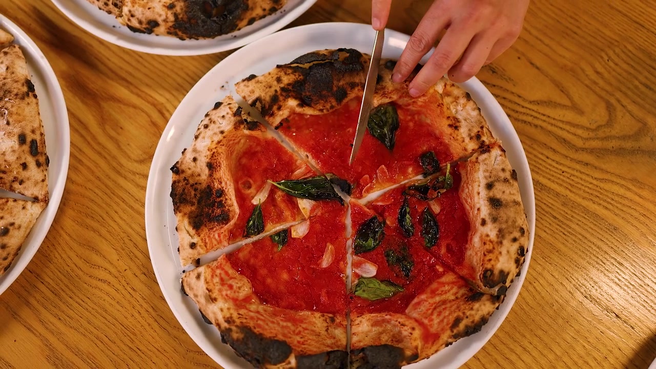 Persona che taglia una pizza napoletana fresca con un coltello