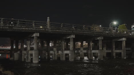 Pedestrians-crossing-bridge-over-Kyoto's-famous-Kamo-River-on-a-cold-winter-night-during-COVID