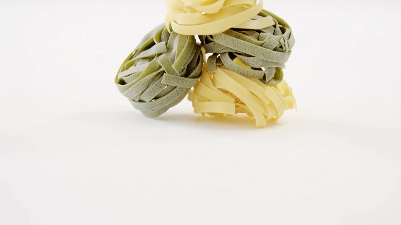 pirámide de pasta tagliatelle verde y amarilla sobre un fondo blanco