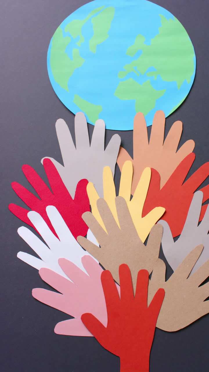 Vertical video of hands with globe made of colourful paper on gray background with copy space