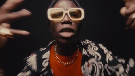 black hip-hop musician in sunglasses and stylish outfit rapping on camera