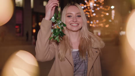 young pretty woman holds up mistletoe and blows you a kiss - in slow motion