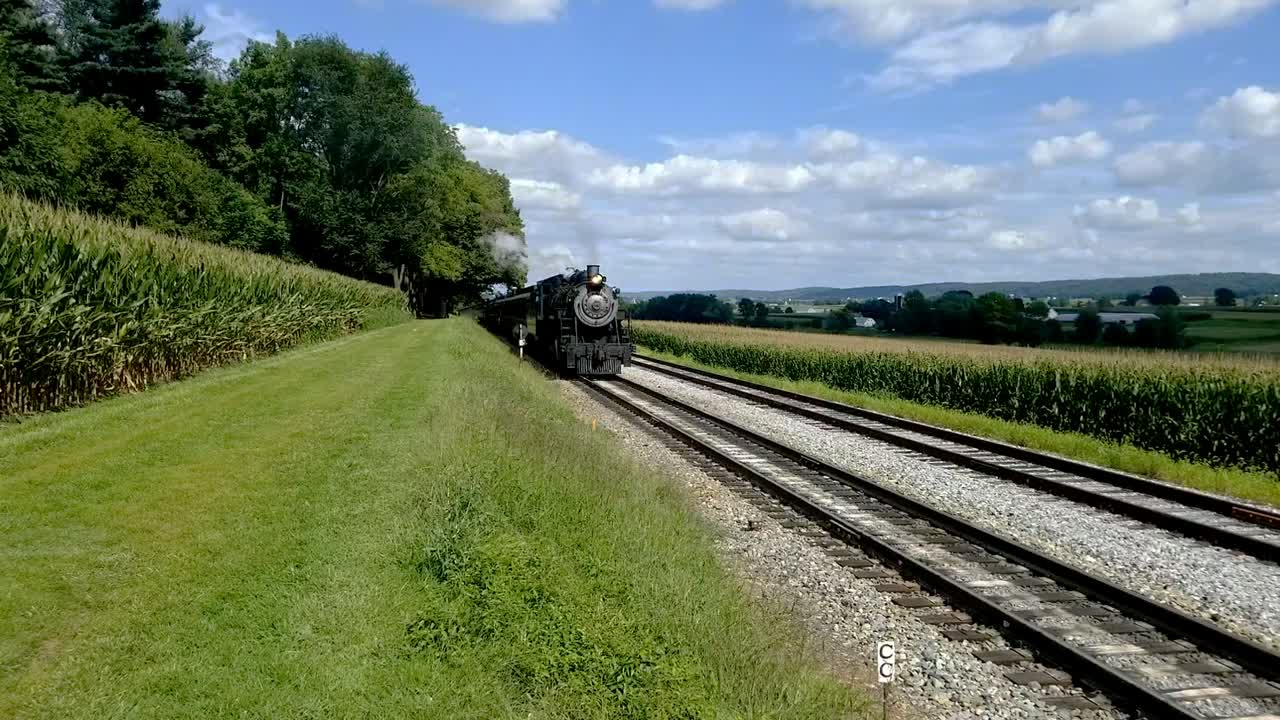 tren de vapor saliendo del área de picnic a lo largo de las tierras de cultivo amish
