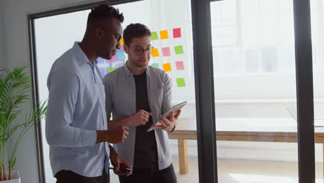 Side-view-of-young-mixed-race-business-team-working-on-digital-tablet-in-a-modern-office-4k