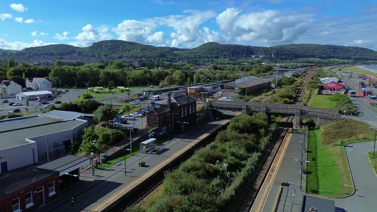 Descending aerial view over Abergele train station and lush Welsh town mountain landscape