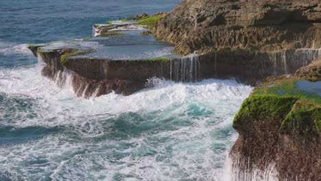 rotating aerial shot of massive waves crashing against rugged cliffs on lembongan island, bali