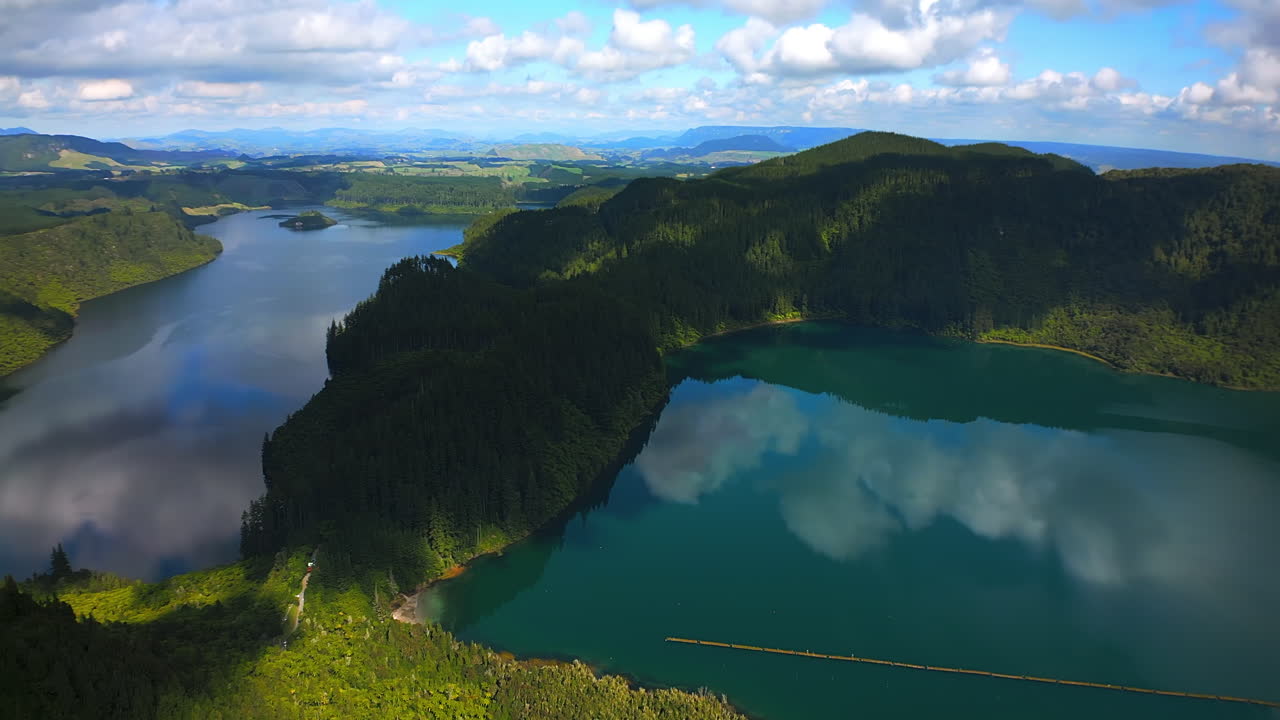 Blue and Green lakes surrounded by lush green hills under a partly cloudy sky in new zealand, aerial