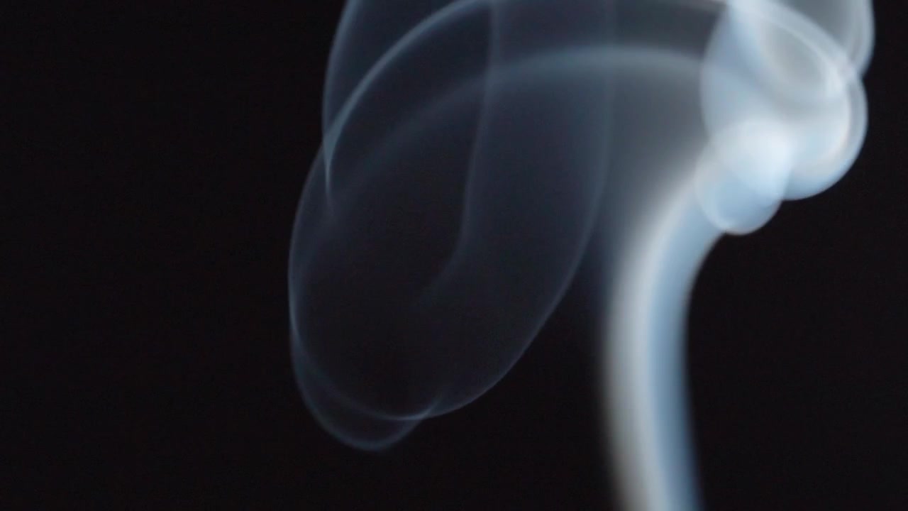Makroaufnahme von wirbelndem Räucherwerkrauch, der fließende Muster vor dunklem Hintergrund bildet und anmutige Bewegung, atmosphärische Details sowie eine duftende Atmosphäre hervorhebt.
