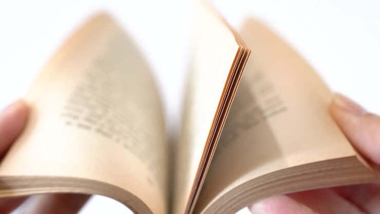 Un vecchio libro di fiabe sfogliato da mani femminili, sfondo bianco.