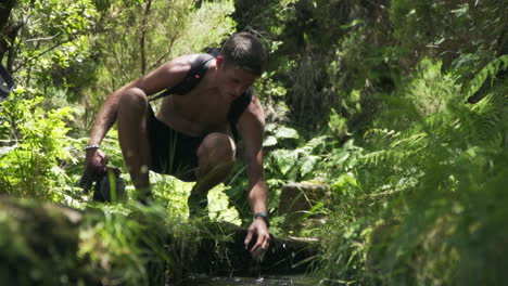 Man-feels-cold-levada-water-in-aqueduct-on-Maderia-Portugal,-slow-motion