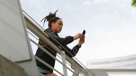 Low-angle-view-of-young-African-American-woman-using-mobile-phone-in-the-city-4k