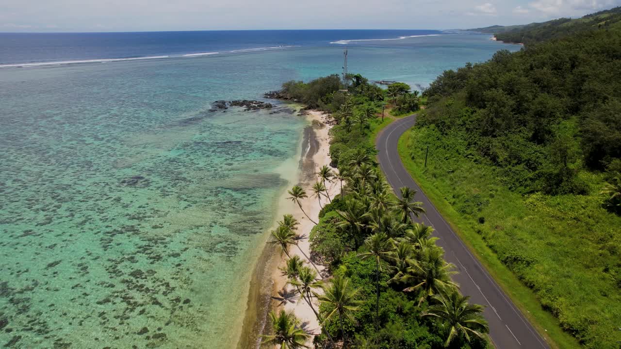 Coastal Road along Tropical Beach in Fiji - aerial pull back with palm trees, sand, blue coral reef