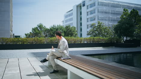 eating boss checking mobile phone screen at summer place. man drinking coffee