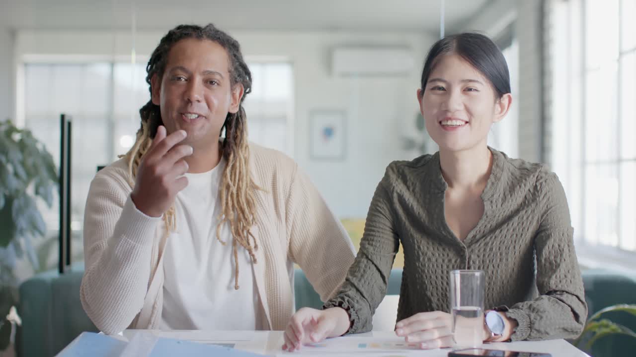 슬로우 모션으로 사무실에서 비디오 통화를 하는 두 명의 행복한 다양한 캐주얼 비즈니스 동료의 초상화