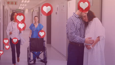 animation of heart icons over caucasian man embracing pregnant wife in hospital