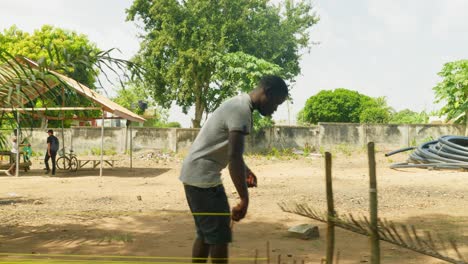Hombre-De-Ghana-Preparando-Textiles-De-Tela-Kente-Entre-Plátanos-En-Una-Aldea-De-Ghana