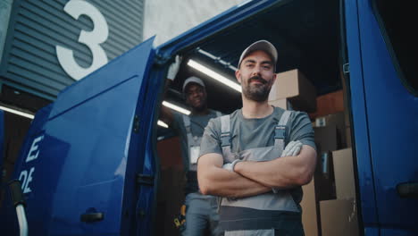 two happy delivery workers posing by their van filled with packages