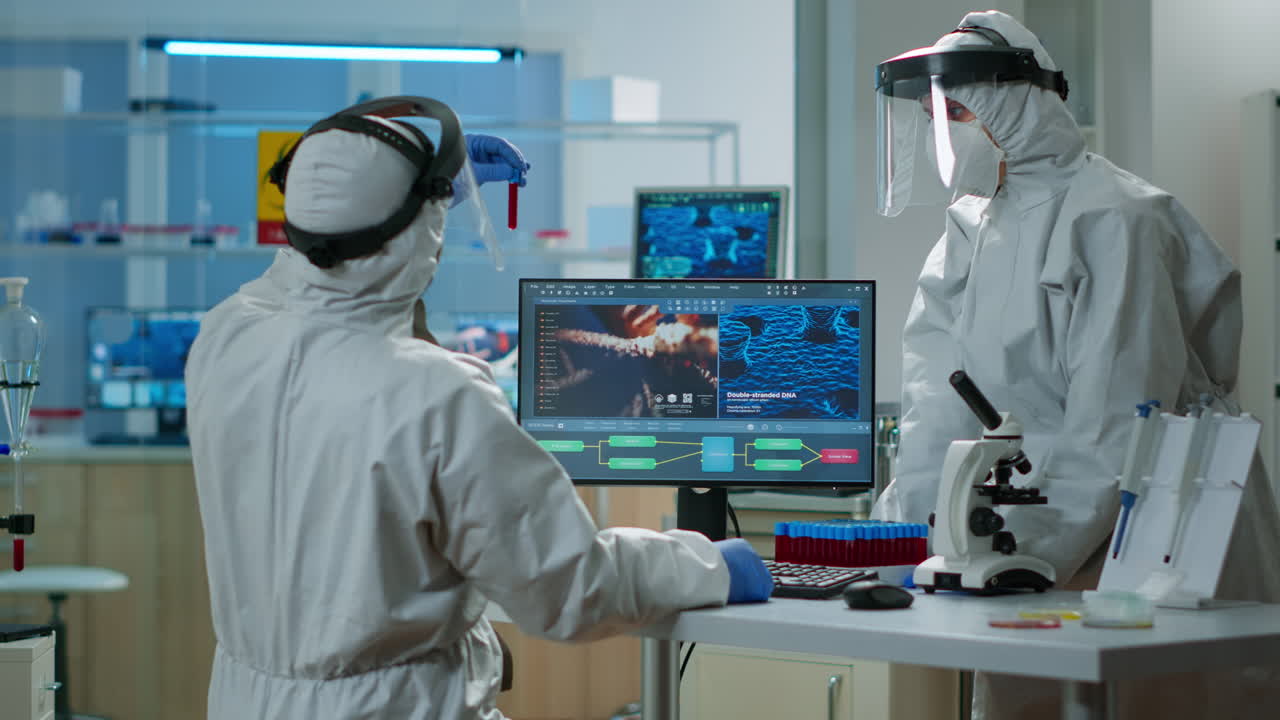 보호복을 입은 과학자들이 혈액 플을 가진 실험 튜브를 분석하고 있습니다.