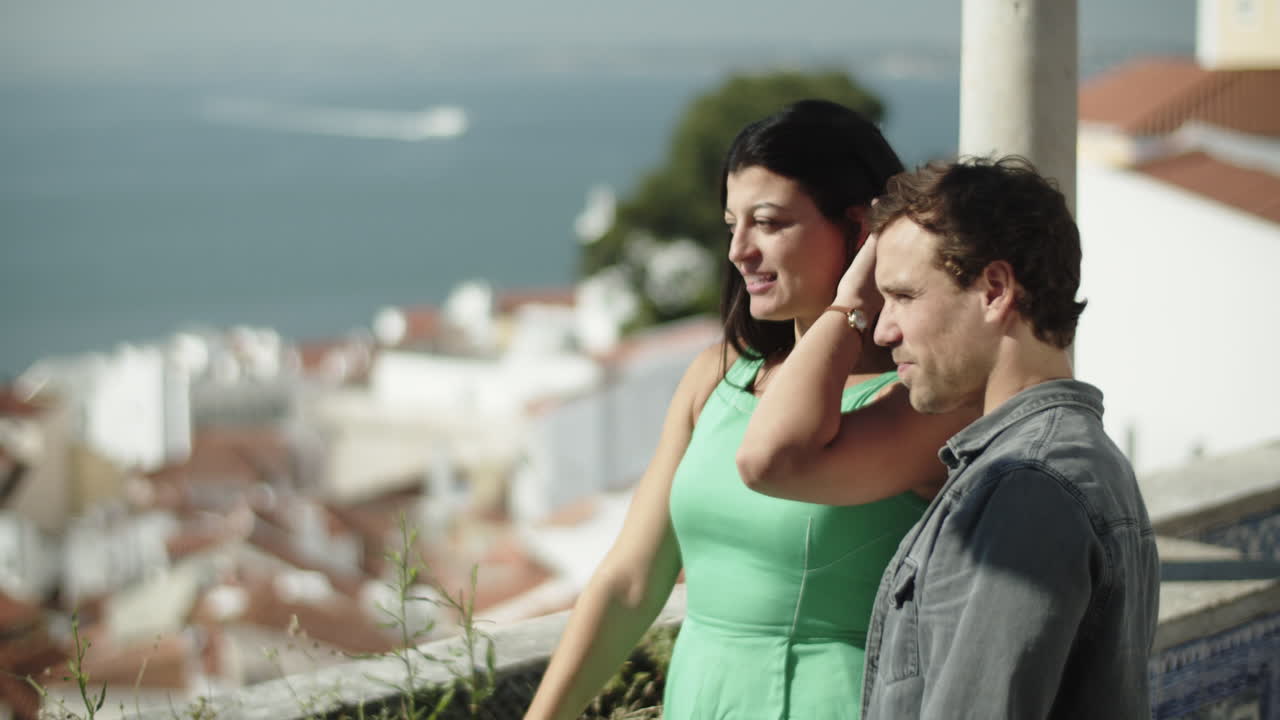 una hermosa pareja de pie junto a la barandilla y disfrutando de la vista del mar.
