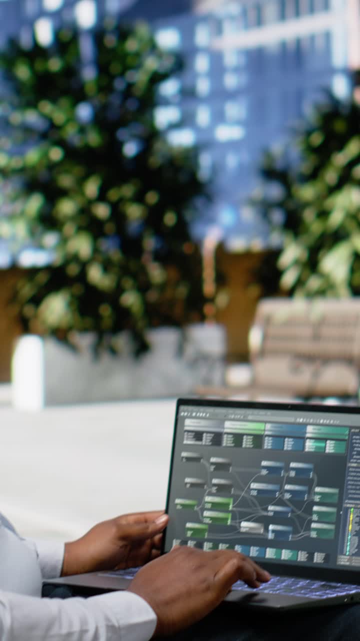Vertical Video African american male engaged in reading data analysis on laptop