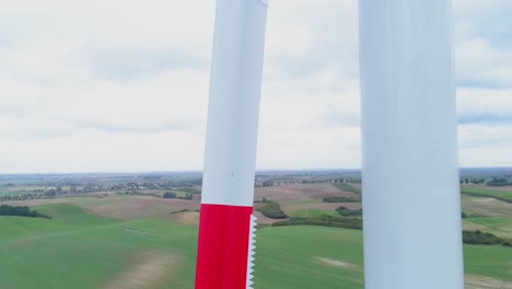 molino de viento pintado de blanco y rojo que no gira con campo verde y fondo de cielo nublado en kwidzyn, polonia - toma de primer plano