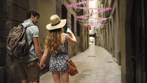 couple taking picture in a narrow alley in barcelona