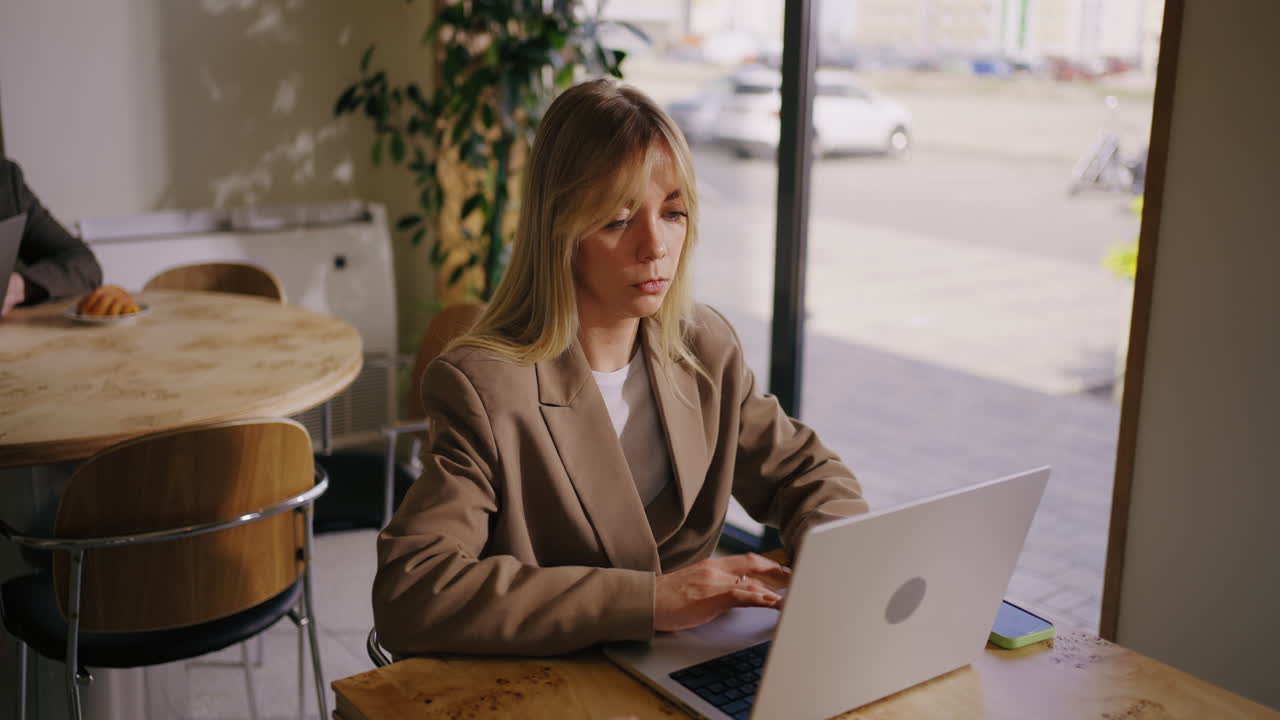 A woman works on her laptop at a coffee shop