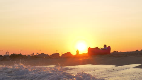 sunset scene of man relaxing in inflatable sunbed at the seaside
