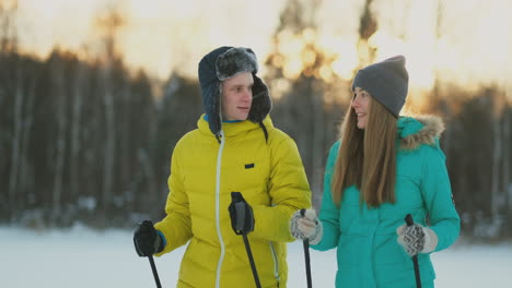 full length portrait of caring young man helping injured girlfriend during ski walk in winter forest