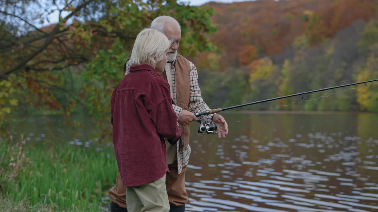 Grandfather and Grandson Fishing by a Lake in Autumn