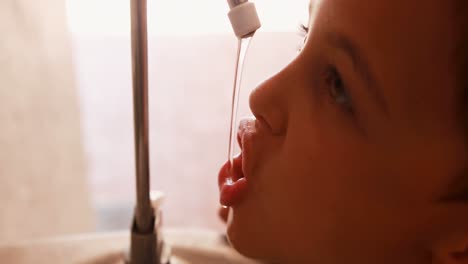 Thirsty-schoolboy-drinking-water-from-faucet-4k