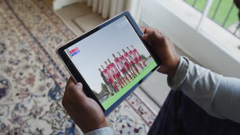 composite of man sitting at home, watching sports event on tablet