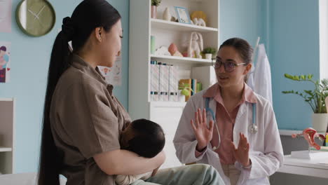 mother breastfeeding her baby with doctor present